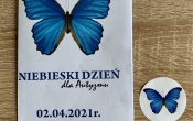Zdjecie ulotki o autyzmie i naklejka z symbolem autyzmu-niebieskiego motyla.