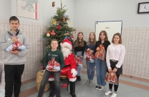 Cztery dziewczyny i dwoje chłopców na tle choinki. Po środku Święty Mikołaj 