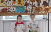 Klaudia i Franio z gr. I z dyplomami i nagrodami na tle prac konkursowych.