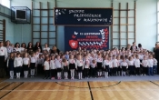Spolecznosc przedszkolna w sali gimnastyczne j przed odspiewaniem hymnu.