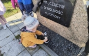 dziewczynka sklada znicz pod pomnikiem Walczacych o wolnosc ojczyzny