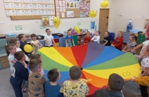 Radosne dzieci z gr. IX podczas zabawy z chusta animacyjna.